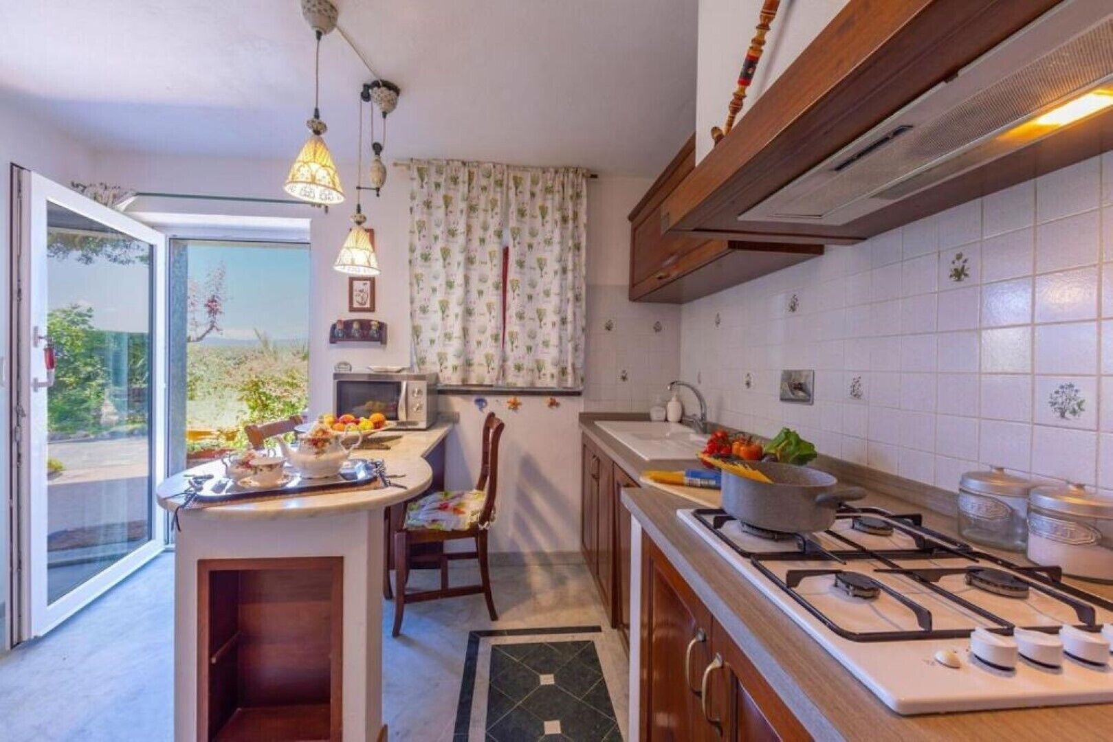 Una cocina compacta con estufa a gas, microondas y comedor con una silla y mesa.