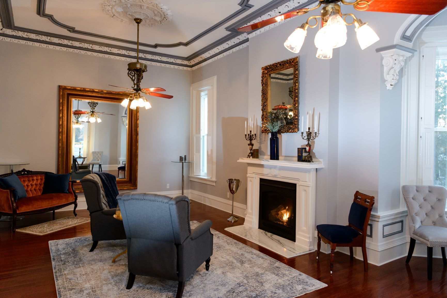 A spacious living room with a fireplace, elegant furniture, and a large mirror.