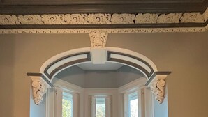 Een kamer met erker, twee gestoffeerde fauteuils, een bijzettafeltje en een buste.