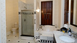 Un baño con ducha de vidrio, un lavabo blanco y una puerta de madera.