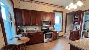 Una cocina con armarios de madera, microondas, estufa y comedor con mesa y sillas.