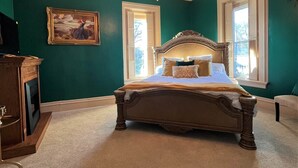 Ein Schlafzimmer mit einem großen Bett, einer Kandelaber, einem Gemälde und einem Kamin.