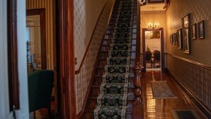 Eine prächtige Treppe mit aufwendiger Teppichböden-Verkleidung, einem Kronleuchter und gerahmten Bildern an der Wand.