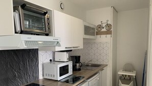 Kompakti keittiö, jossa on sisäänrakennettu mikroaaltouuni, leivänpaahdin ja kahvinkeitin.