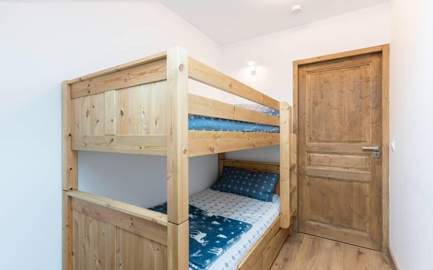 A bunk bed with a wooden frame and a door to the right.