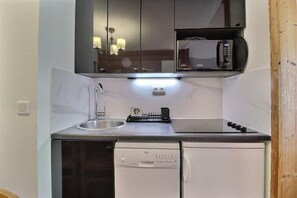 A compact kitchen with a built-in microwave, a sink, and a dishwasher.