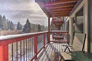 A wooden deck with a red railing, a table, and a chair. - Idyllic Condo ~ 5 Mi to Winter Park Resort! (Winter Park)
