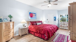 Une chambre à coucher comprenant un lit, une commode, des tables de chevet et un ventilateur de plafond.