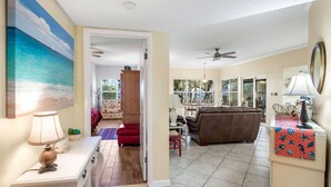 A spacious living area with a sofa, dining table, and a ceiling fan. - Hidden Dunes Beach Cottage 178 - Charming Beach Cottage! (Miramar Beach)