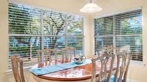 A dining area with a round wooden table, blue tablecloth, and wooden chairs. - Hidden Dunes Beach Cottage 178 - Charming Beach Cottage! (Miramar Beach)