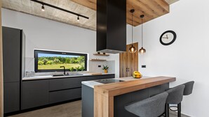 Une cuisine moderne dotée d’une grande fenêtre, d’un téléviseur encastré et d’un îlot central en bois avec des tabourets de bar.