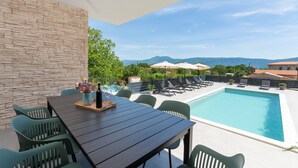 Un espace aménagé au bord de la piscine, avec une table et des chaises, une piscine et une vue sur les montagnes.