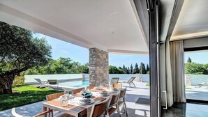 Un espace de restauration extérieur moderne, offrant une vue sur une piscine et une végétation luxuriante.