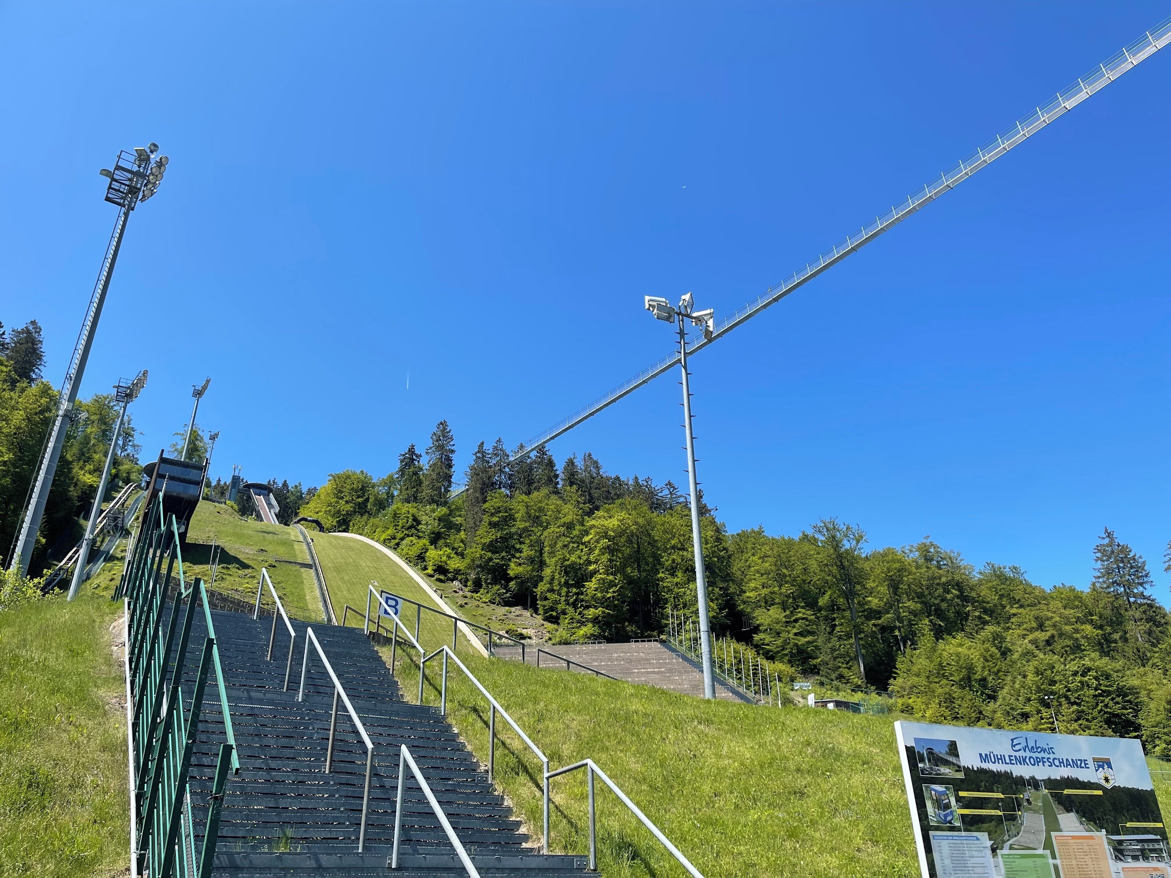 A set of outdoor stairs leading up a grassy slope with a signboard at the top.