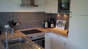 Een moderne keuken met een roestvrijstalen spoelbak, een inbouwoven, een koffiezetapparaat en een magnetron.