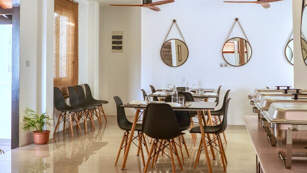 Un espace repas moderne avec un plancher poli, des ventilateurs de plafond et une table à manger avec des chaises.