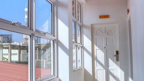 Un couloir doté de grandes fenêtres, d’un plafond en bois et d’une porte blanche.