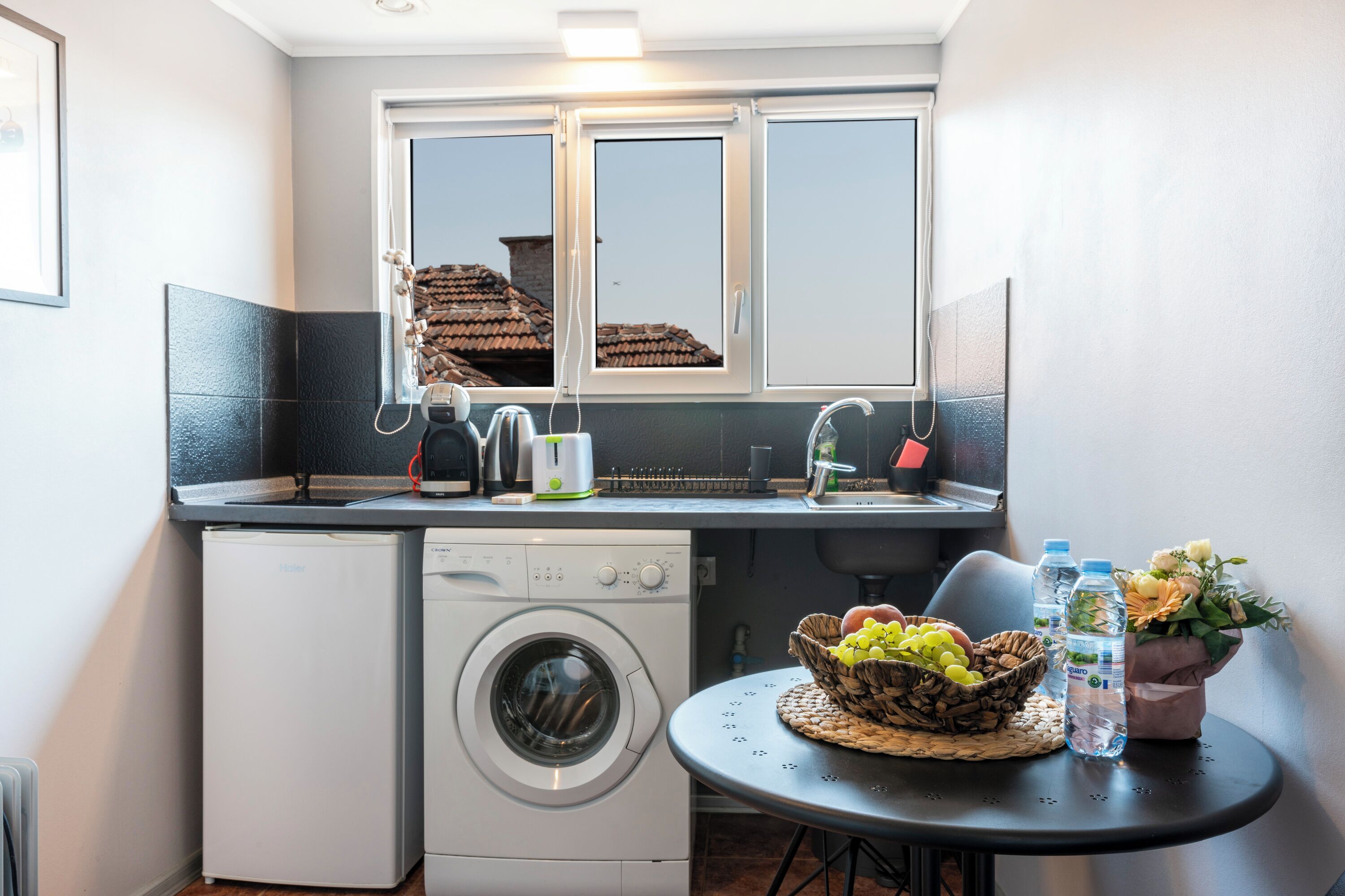 Een koffiezetapparaat/waterkoker, kookgerei, borden en bestek, eettafels