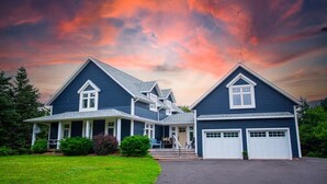 Ett tvåvåningshus med en veranda på framsidan, ett garage och en uppfart.