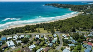 Vista aérea de una zona residencial costera con casas, una playa y un área boscosa.