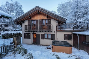 A two-story chalet with a balcony, wooden exterior, and a hot tub in the yard. - Chalet le Tremplin, Hot tub - Chamonix All Year (Chamonix)