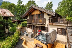 A chalet with a wooden deck, outdoor seating, and a hot tub. - Chalet le Tremplin - sleeps 6 in 2 bedrooms with hot tub (Chamonix)
