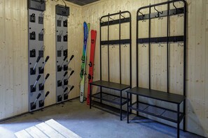 A ski storage room with metal racks for skis and a bench.