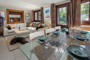 Comedor con una mesa de vidrio dispuesta para seis personas, rodeado de sillas blancas.