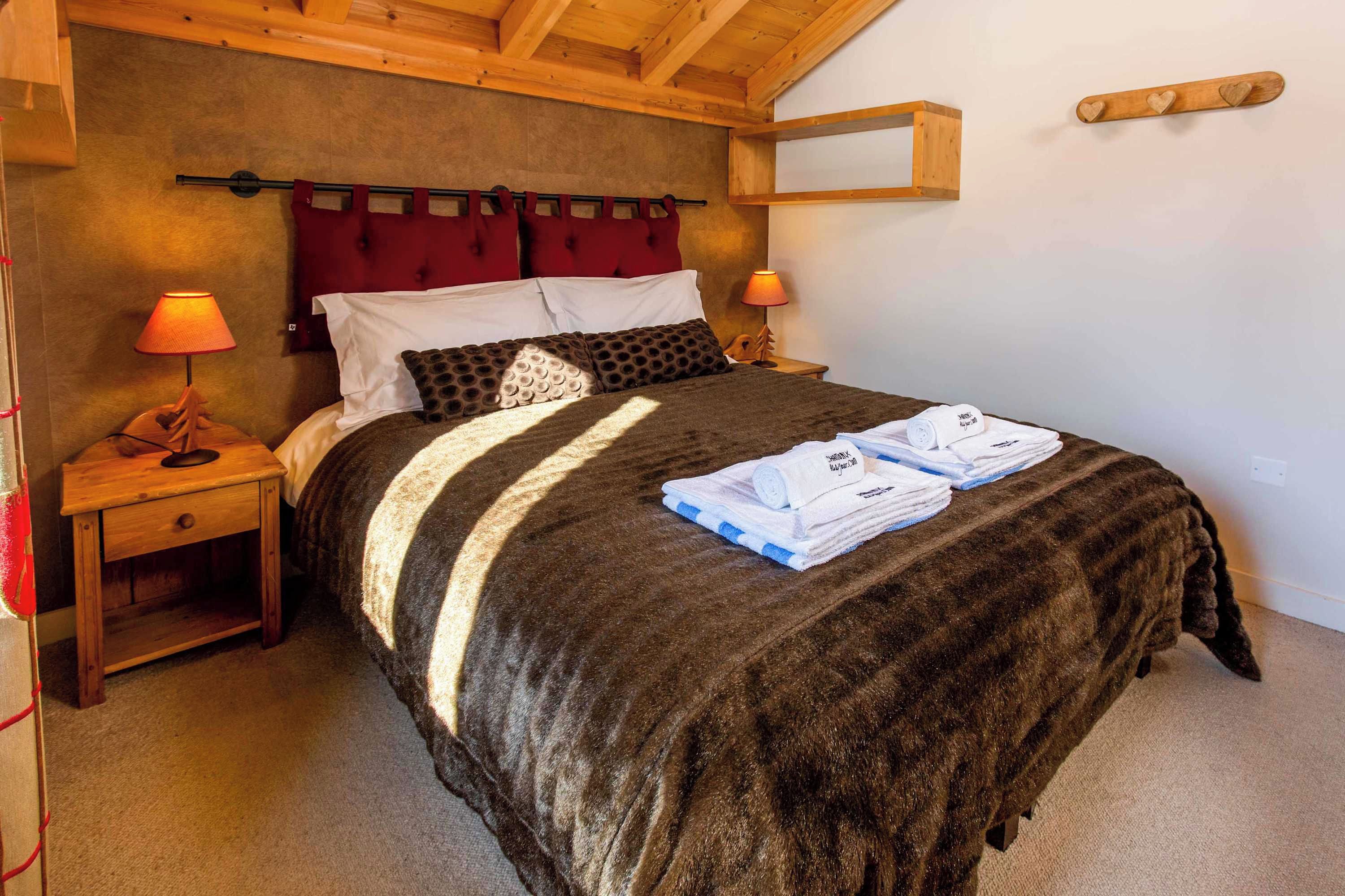 Ein Schlafzimmer mit einem Bett, zwei Nachttischen, einer Lampe und einem Holzkopfende.