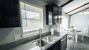 Una cocina moderna con encimeras de granito, pileta de acero inoxidable y muebles oscuros.