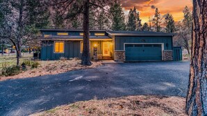A modern two-story house with a garage, surrounded by trees and a driveway. - Modern Tollgate Home - HOT TUB, Half Acre Lot (Sisters)
