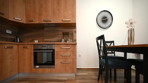 Une cuisine moderne avec des meubles en bois, un four encastré et un coin repas comprenant une table et des chaises.