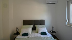 Une chambre à coucher comprenant un lit, deux tables de chevet, un appareil de climatisation et une fenêtre.