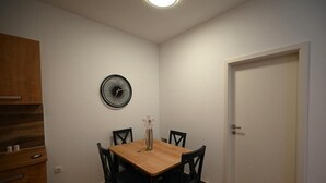 Un petit coin repas avec une table en bois et quatre chaises, une horloge murale et une porte.