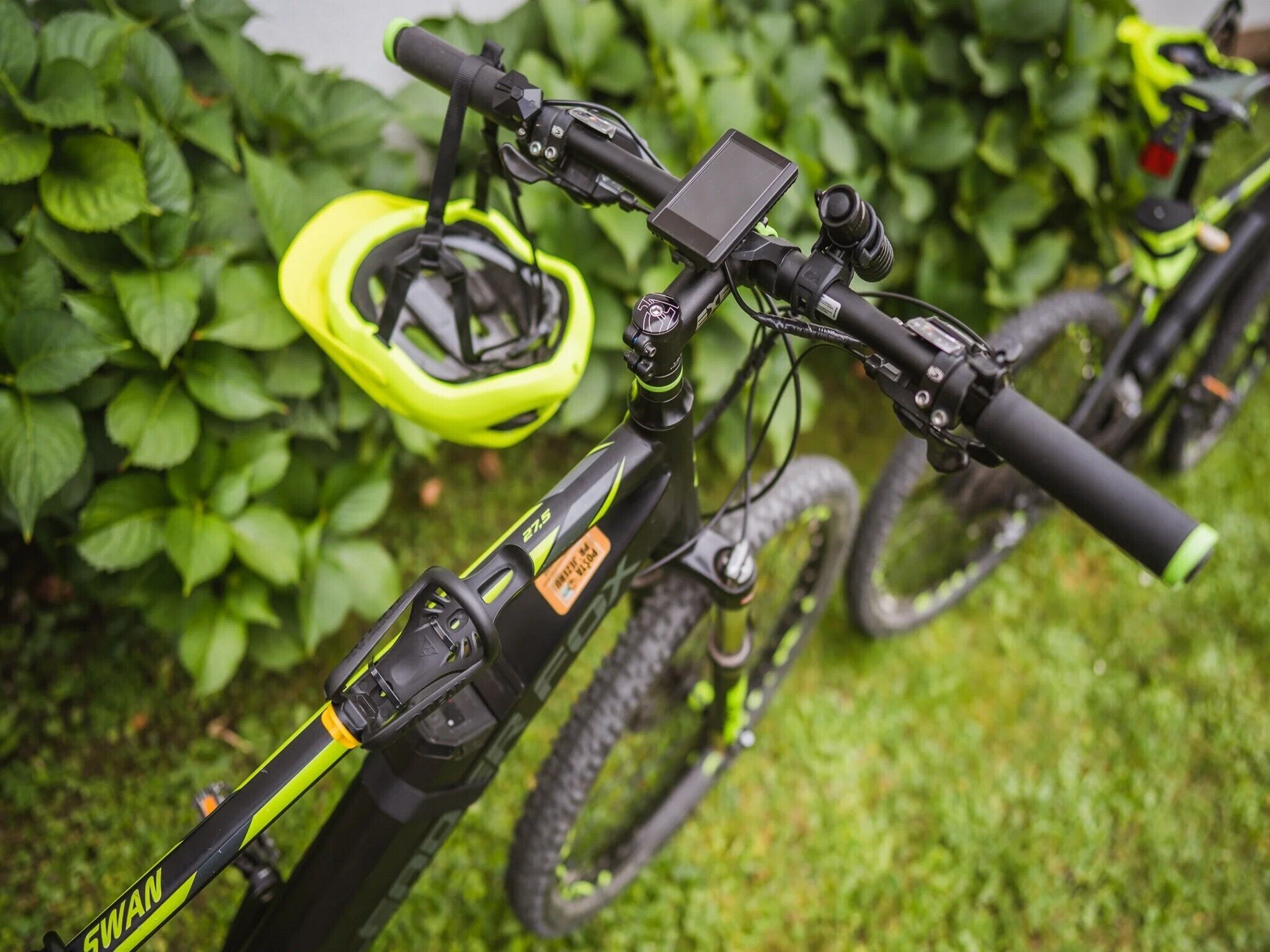 Un vélo tout-terrain équipé d’une fourche à suspension avant, d’un appareil fixé au guidon et d’un casque jaune accroché au vélo.