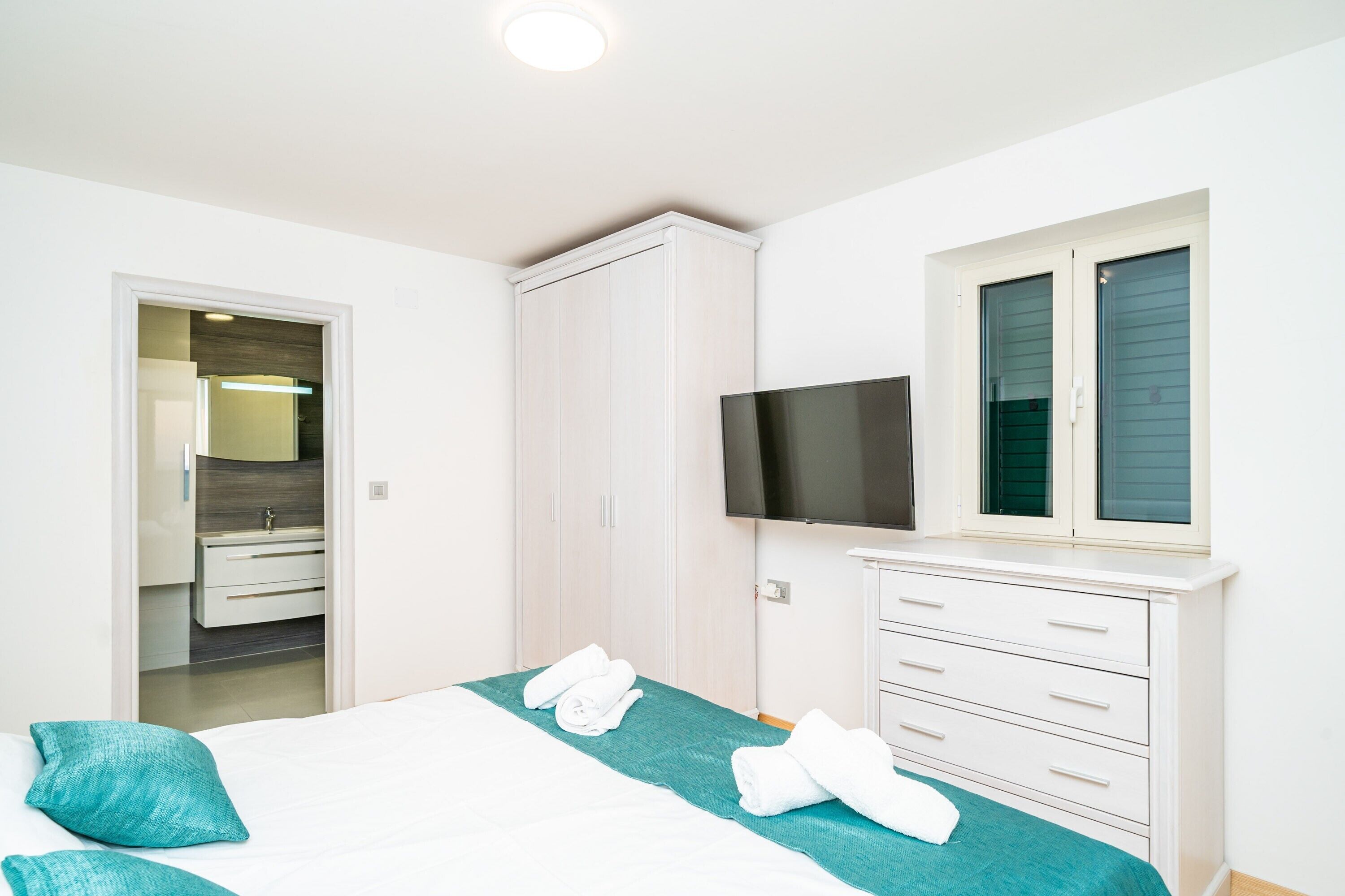 A hotel room with a bed, a TV, a wardrobe, and a window.