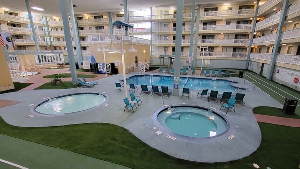 A multi-level hotel with two indoor pools, each surrounded by lounge chairs and a small garden area. - RENOVATED LUXURY BEACH VILLA,Ocean view,3 bdrms each with smart tv and king bed (Hilton Head Island)