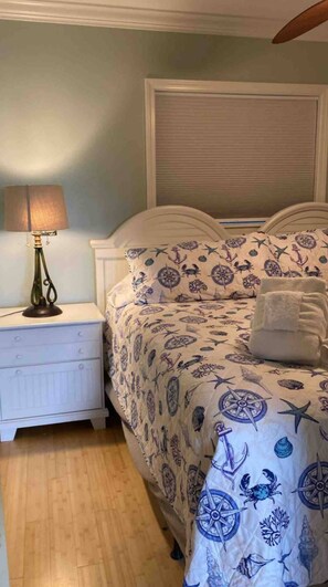 A bedroom with a bed, nightstand, lamp, and a window with blinds. - RENOVATED LUXURY BEACH VILLA,Ocean view,3 bdrms each with smart tv and king bed (Hilton Head Island)