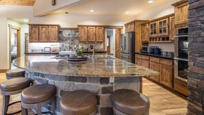 A spacious kitchen with a large island, wooden cabinets, and a stone accent wall.