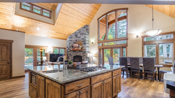 A spacious kitchen with a large island, wooden cabinets, and a stone fireplace.
