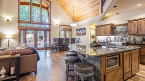 A spacious kitchen with a large island, wooden cabinets, and a stone backsplash.