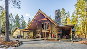 A lodge with a stone fireplace, wooden exterior, and a driveway leading to the entrance.