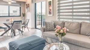Un salon moderne comprenant un canapé, une table basse et un coin repas avec des chaises et une table.