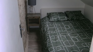 Un dormitorio con una cama, una lámpara de noche y una mesita de noche.