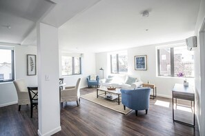 A modern living room with a sofa, chairs, a coffee table, and a small side table. - New building, fully equipped apt, steps to all Boston has to offer! (Boston)