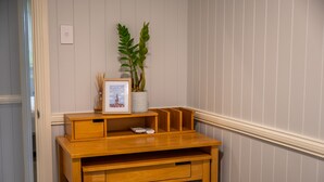 A wooden desk with drawers and a vase with a plant. - Oasis on the Esplanade (Manly)