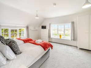A bedroom with a bed, a window, a TV, and a wardrobe.