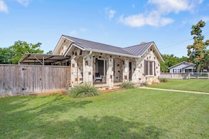 A single-story house with a stone facade, a covered porch, and a fenced yard.
