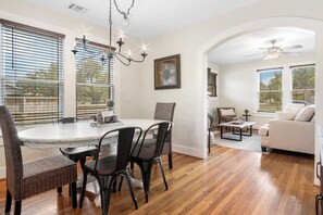 Amplia sala de estar con comedor, piso de madera y ventanas grandes.