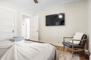 A bedroom with a bed, a chair, a television, and a door.
